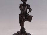 une figurine antique en bronze représentant un garçon tenant un panier