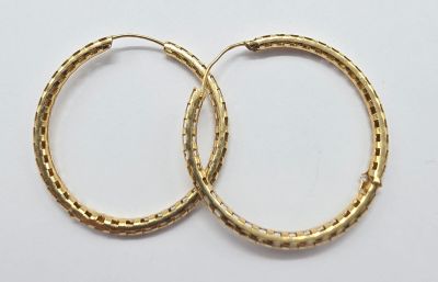 deux paires de boucles d'oreilles en or sur fond blanc