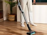 un homme en train de passer l'aspirateur sur un parquet dans un salon