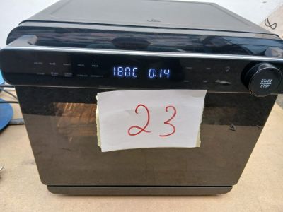 une horloge fixée sur la façade d'un lave-vaisselle, sur laquelle est collé un bout de papier