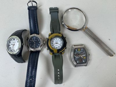 three watches and a magnifying glass on a table