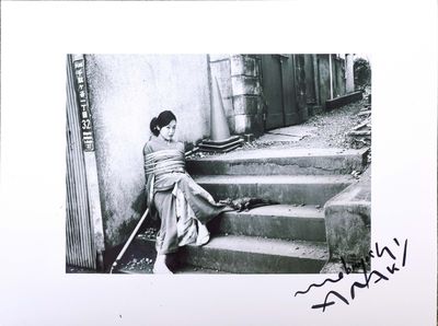 a black and white photo of a woman sitting on the steps