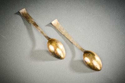 deux cuillères en argent posées l'une à côté de l'autre sur une table