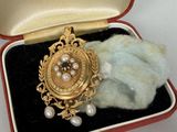 une broche en or sertie de perles, dans un écrin