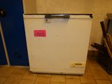 a small white refrigerator with a pink sticker on it
