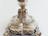 a silver plate with a silver vase on top of it