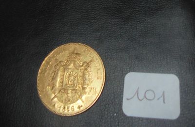 une pièce d'or posée à côté d'un autocollant sur une surface noire