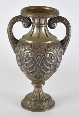 un vase en argent posé sur une surface blanche