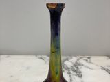 un vase en verre violet et vert posé sur un plan de travail en marbre