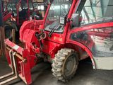 a red tractor that is parked inside of a building