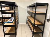 deux étagères dans un coin de la pièce, sur lesquelles sont posées des cartons