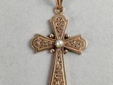 a gold cross with a pearl in the center on a white background