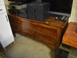 a television on a dresser next to a refrigerator and a refrigerator
