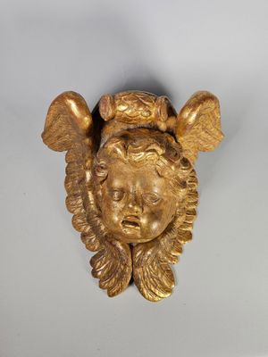 une image représentant une statue en or représentant la tête d'un enfant posée sur une surface blanche