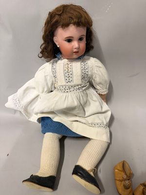 une poupée allongée par terre à côté d'une paire de chaussures
