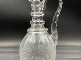 a clear glass vase with a handle on a table