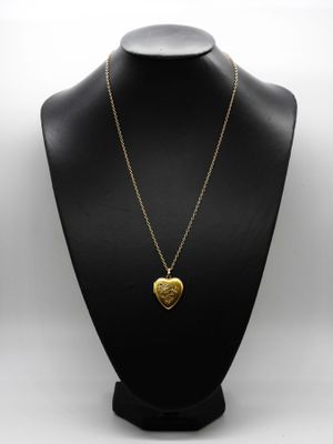 a gold heart pendant on a black mannequin necklace