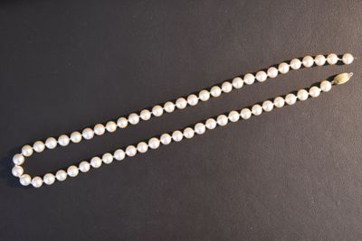 a close up of a white beaded necklace on a black surface