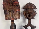 une paire de masques africains sculptés dans le bois, exposés sur une table bleue