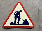 un panneau triangulaire sur lequel figure l'image d'un homme en train de pelleter de la terre