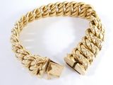 gros plan d'un bracelet en or sur une surface blanche