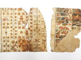 deux morceaux de vieux papier comportant des motifs, posés sur une surface blanche