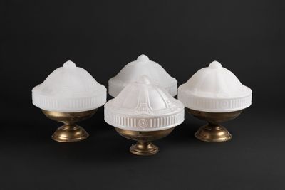 trois lampes en verre blanc avec des pieds dorés sur fond noir