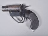 un vieux pistolet avec un canon en métal posé sur une surface blanche