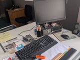 a desk with a computer, keyboard, phone, and other office supplies on it