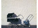 a baby carriage and a stroller next to a white wall