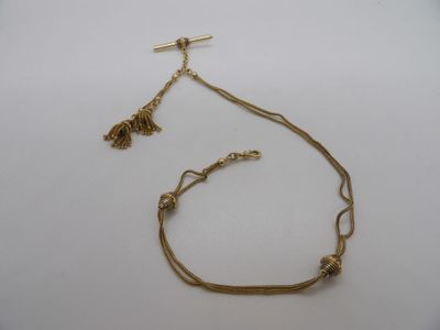 un gros plan d'un collier en or orné d'un pompon, posé sur une surface blanche
