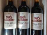 trois bouteilles de vin rouge dans une boîte blanche posée sur une table