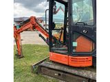 an orange and black excavator sitting on top of a grass covered field