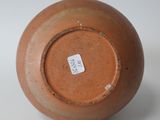 a brown vase with a tag on it on a white surface