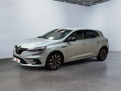 La voiture argentée est garée dans une grande pièce aux murs blancs.