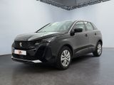 Une voiture noire est garée dans une grande pièce aux murs blancs.