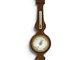 a wooden clock hanging on the wall with a barometer on it