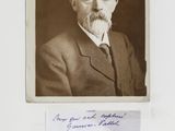 an old photo of a man in a suit and tie with a handwritten note in front of him