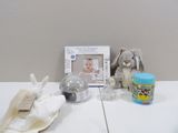 une photo représentant un biberon, un cadre photo et une peluche posés sur une table