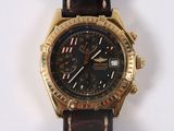 a gold watch with a black face on a brown strap
