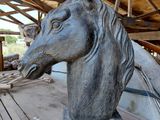 une statue représentant une tête de cheval posée sur un socle en bois