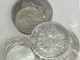 three silver coins in a plastic bag on a white surface