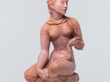 une petite statue représentant une femme assise sur une surface blanche
