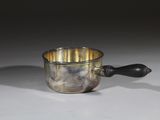 une tasse en argent avec une anse noire posée sur une table