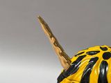 a yellow and black painted pumpkin with a stick sticking out of it
