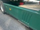 a green truck with a flat bed in the back