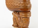 un grand bol en bois posé sur un socle, sur fond blanc