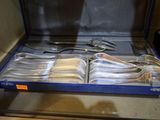 un service en argent dans un coffret bleu posé sur une table