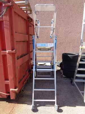 a ladder that is sitting next to a red dumpster