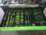 une boîte à outils verte remplie d'outils, posée par terre